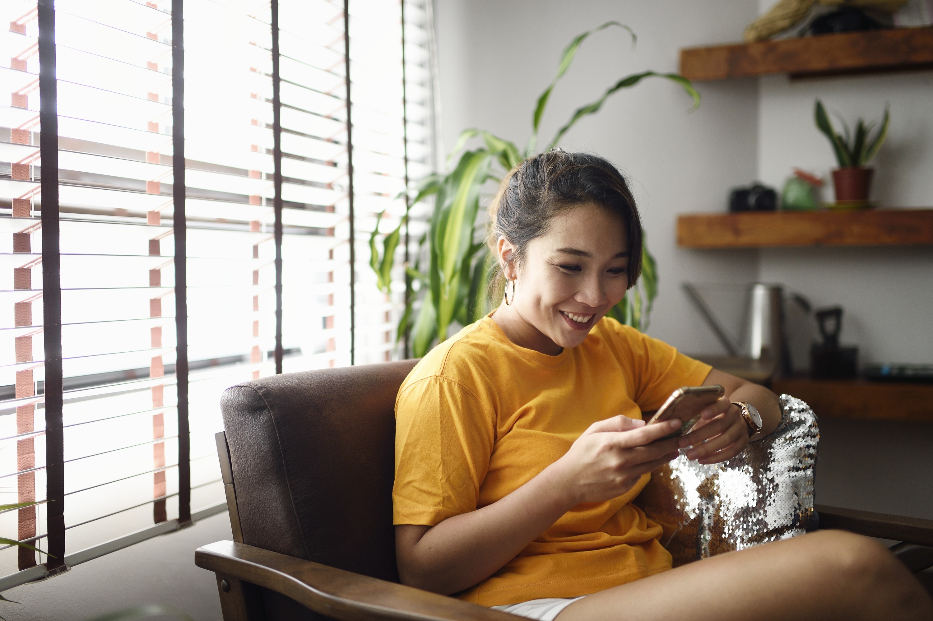 Young woman at home looking at cash ISA options on phone