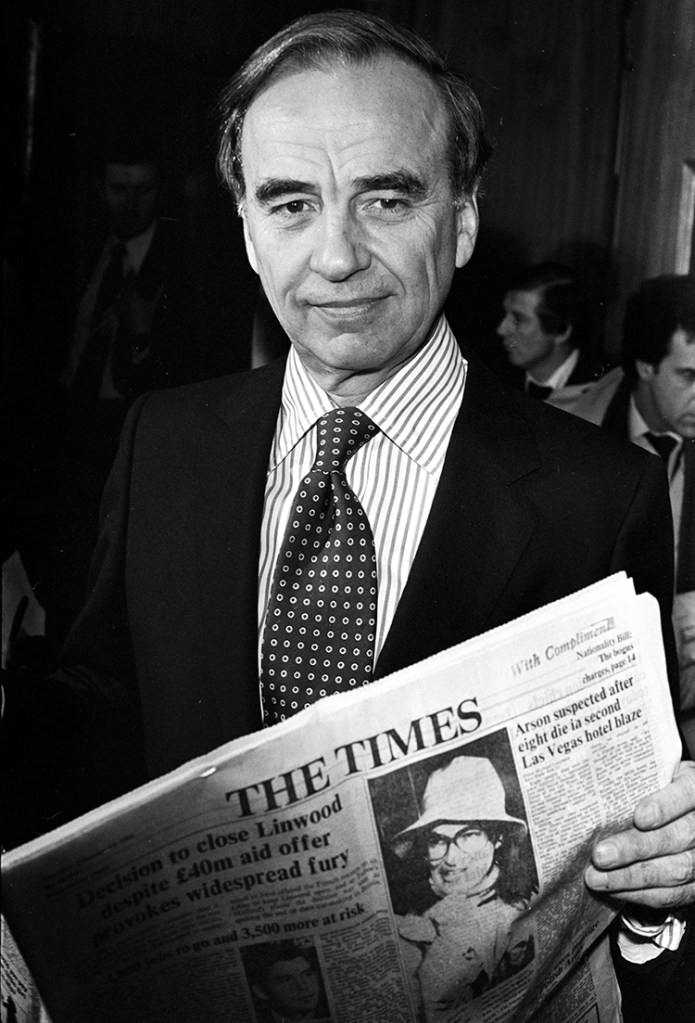 Black and white photo of Rupert Murdoch holding a copy of The Times