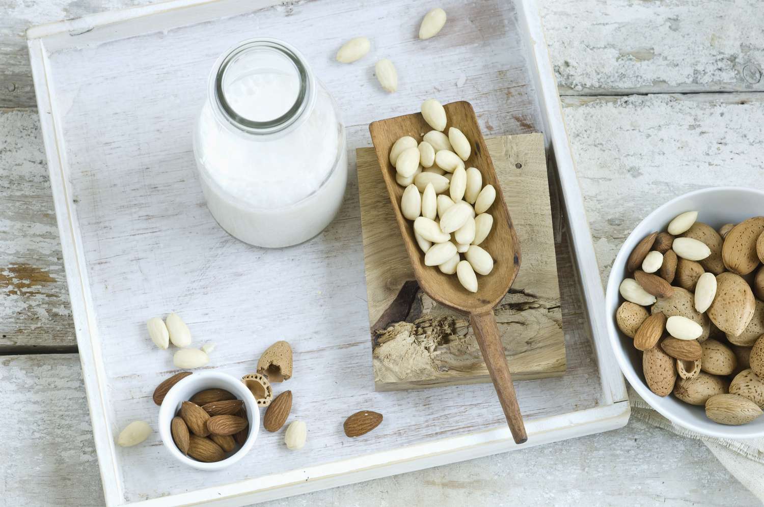 Glass bottle of almond milk surrounded by whole almonds