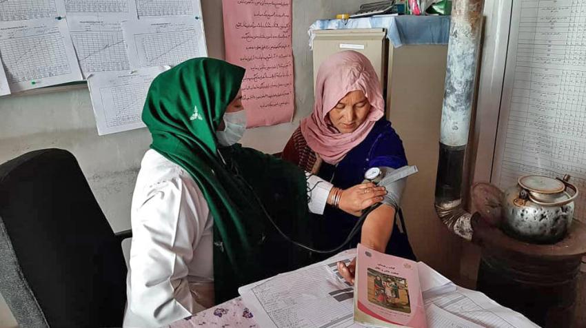 Акушерка измеряет кровяное давление у женщины в семейном доме здоровья в сельской местности Афганистана.