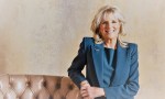 La Dra. Jill Biden luciendo un traje azul, de pie junto a un sillón de cuero