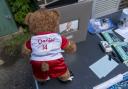 A teddy bear in an Arsenal top on a table at vigil at Hainault Underground Station Car Park, in memory of 14-year-old Daniel Anjorin