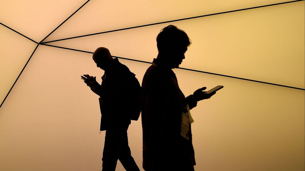 Silhouettes of two men using their smart phones