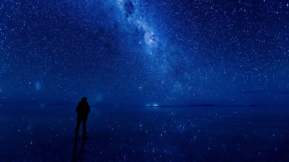 A person looking at stars reflected in a lake (Credit: Getty Images)