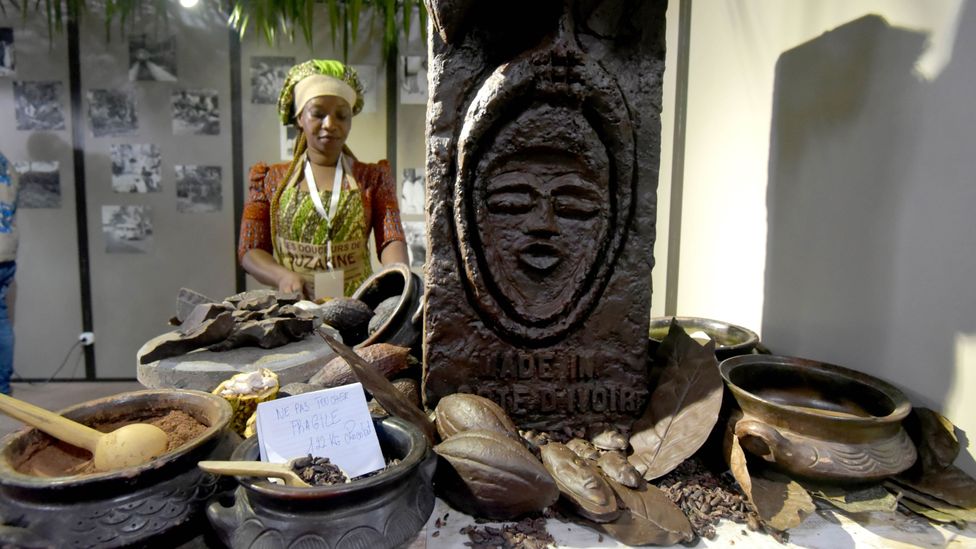 A woman stands by a cocoa stall in Ivory Coast (Credit: Getty Images)