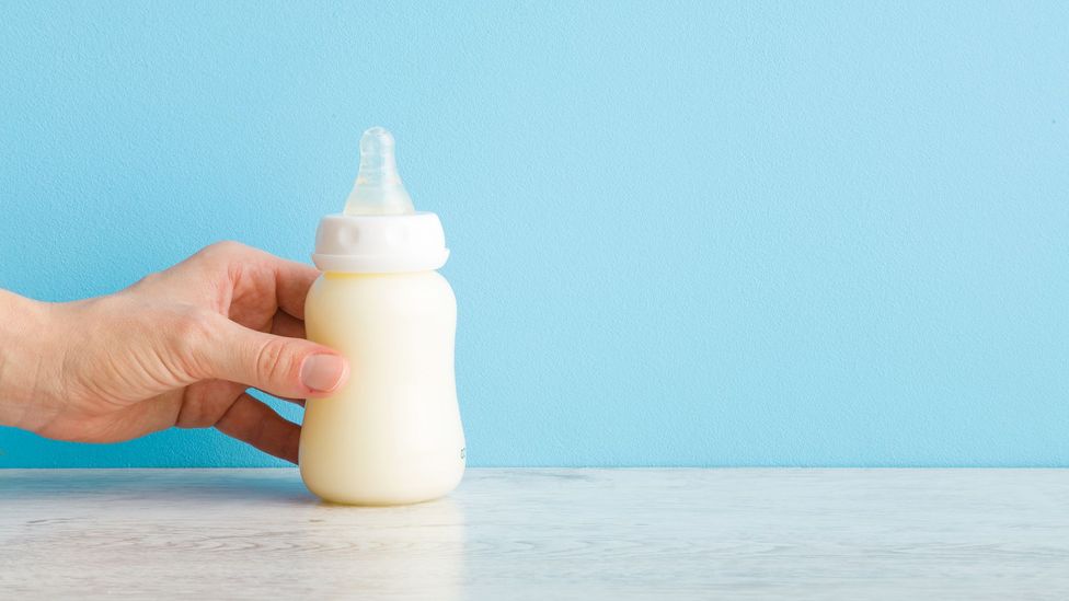 Man's hand on baby's bottle (Credit: FotoDuets/Getty Images)