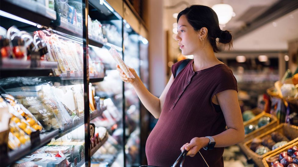 A woman inspects different products in a supermarket (Credit: Getty Images)